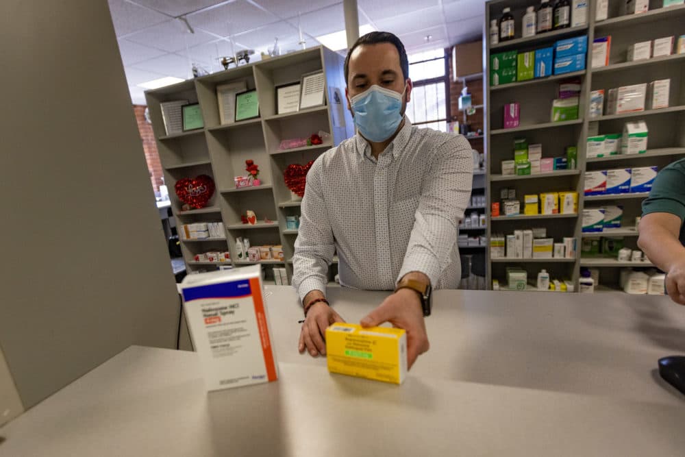 Pharmacist Andrew Terranova places a box each of Narcan and Suboxone in the window counter at Genoa Healthcare pharmacy. (Jesse Costa/WBUR)