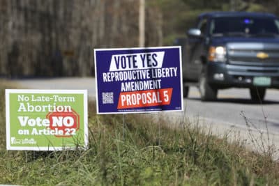 A truck drives by campaign signs opposing and supporting a proposed amendment to the Vermont constitution that would guarantee access to reproductive rights, including abortion, by the side of the road in on Nov. 3, 2022 in Middlesex, Vt. (Wilson Ring/AP)