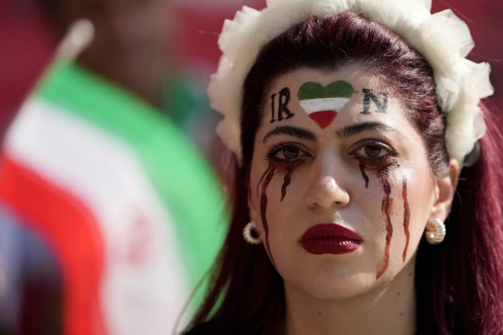 A woman stands on the tribune with her face painted in memory of Mahsa Amini, a woman who died while in police custody in Iran at the age of 22, prior to the World Cup group B soccer match between Wales and Iran, at the Ahmad Bin Ali Stadium in Al Rayyan , Qatar, Friday, Nov. 25, 2022. (Frank Augstein/AP)