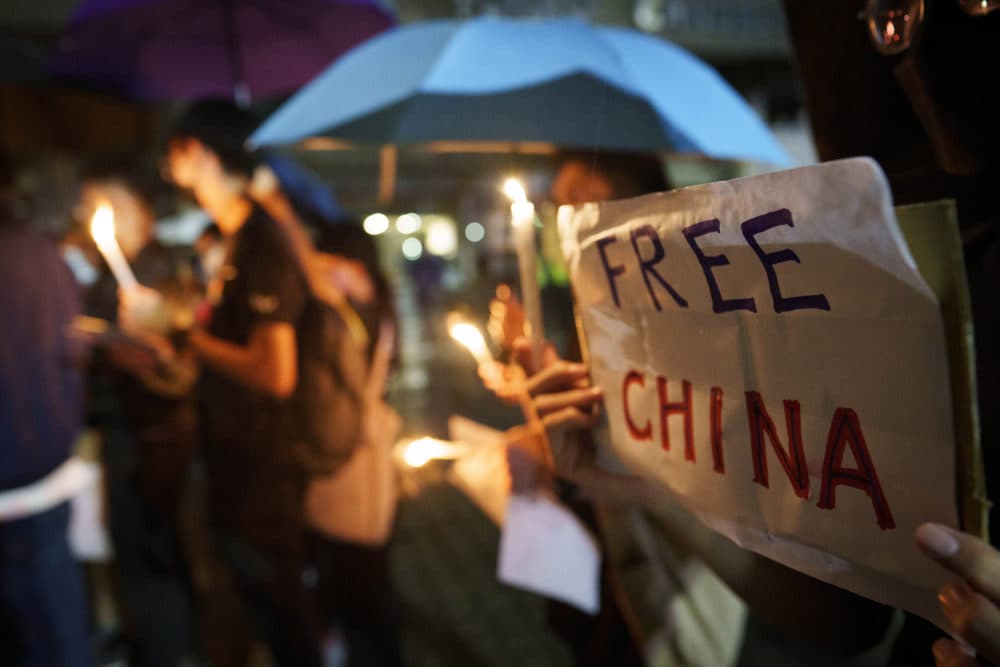 Student protesters hold up candles and placards during a commemoration for victims of a recent Urumqi apartment deadly fire blamed on the rigid anti-virus measures, held in Kuala Lumpur, Malaysia, Tuesday, Nov. 29, 2022. On Tuesday, about a dozen people gathered at the University of Malaya, chanting against virus restrictions and holding up sheets of paper with critical slogans. (Vincent Thian/AP)