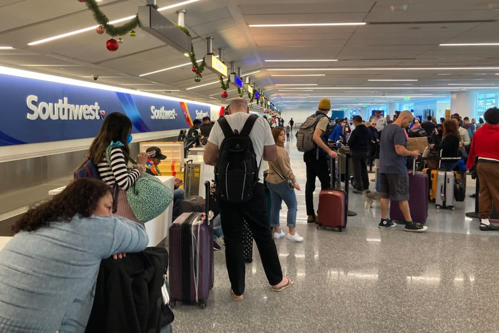 Travelers wait at a Southwest Airlines baggage counter to retrieve their bags after canceled flights at Los Angeles International Airport. (Eugene Garcia/AP)