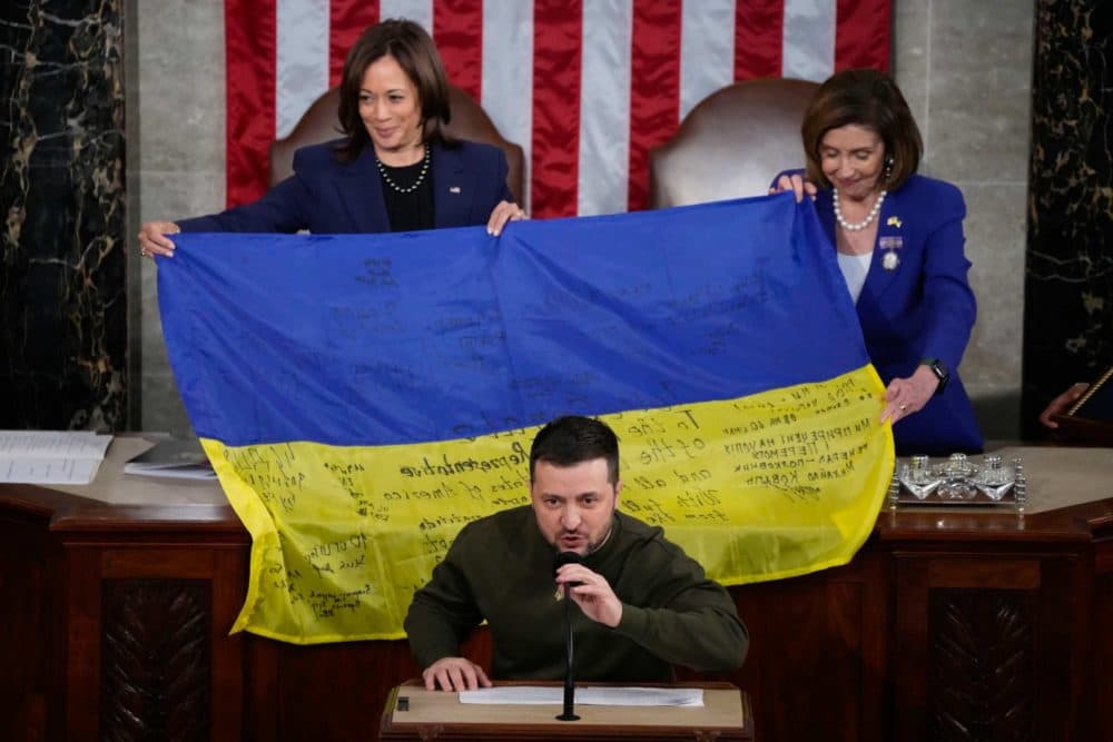 Vice President Kamala Harris and House Speaker Nancy Pelosi react as Ukrainian President Volodymyr Zelenskyy presents lawmakers with a Ukrainian flag autographed by front-line troops in Bakhmut, in Ukraine's contested Donetsk province, as he addresses a joint meeting of Congress on Capitol Hill in Washington, Wednesday, Dec. 21, 2022. (Jacquelyn Martin/AP)