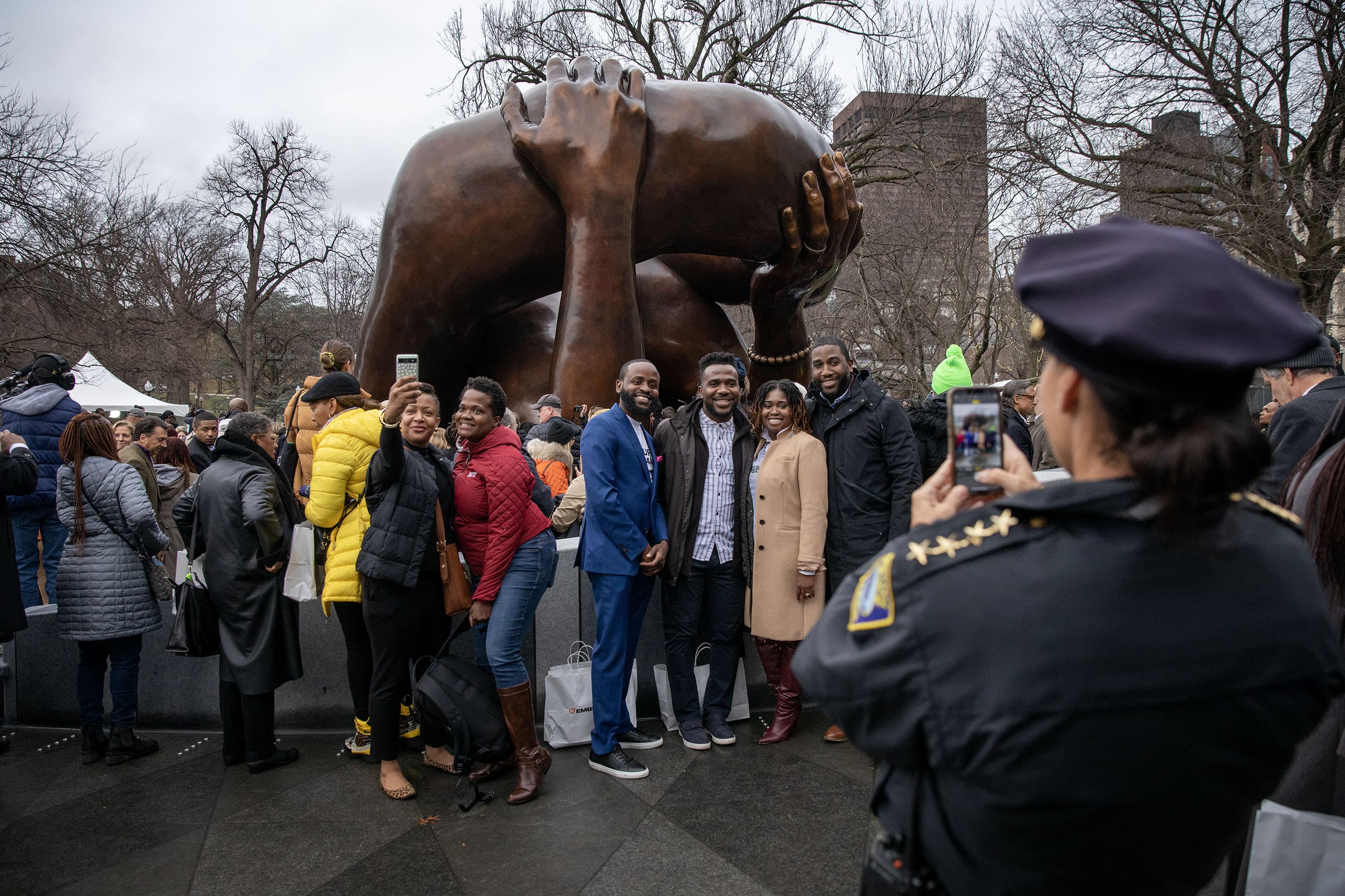 Attendees at the ceremony celebrate and takes selfies in front of the newly unveiled Embrace sculpture on Boston Common. (Robin Lubbock/WBUR)