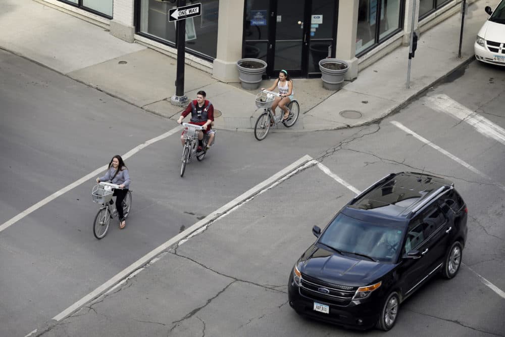 Cyclists riding rental bikes make their way through a downtown intersection, in Des Moines, Iowa. (Charlie Neibergall/AP)