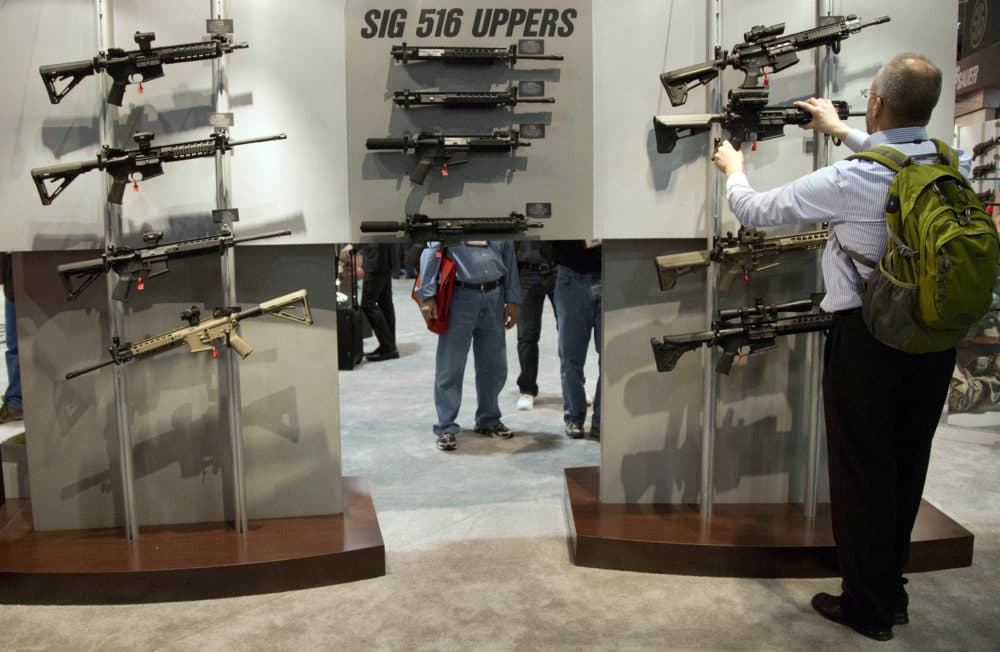 A convention attendee looks through a display of Sig Sauer semiautomatic rifles during the 35th annual SHOT Show, Tuesday, Jan. 15, 2013, in Las Vegas. (Julie Jacobson/AP)