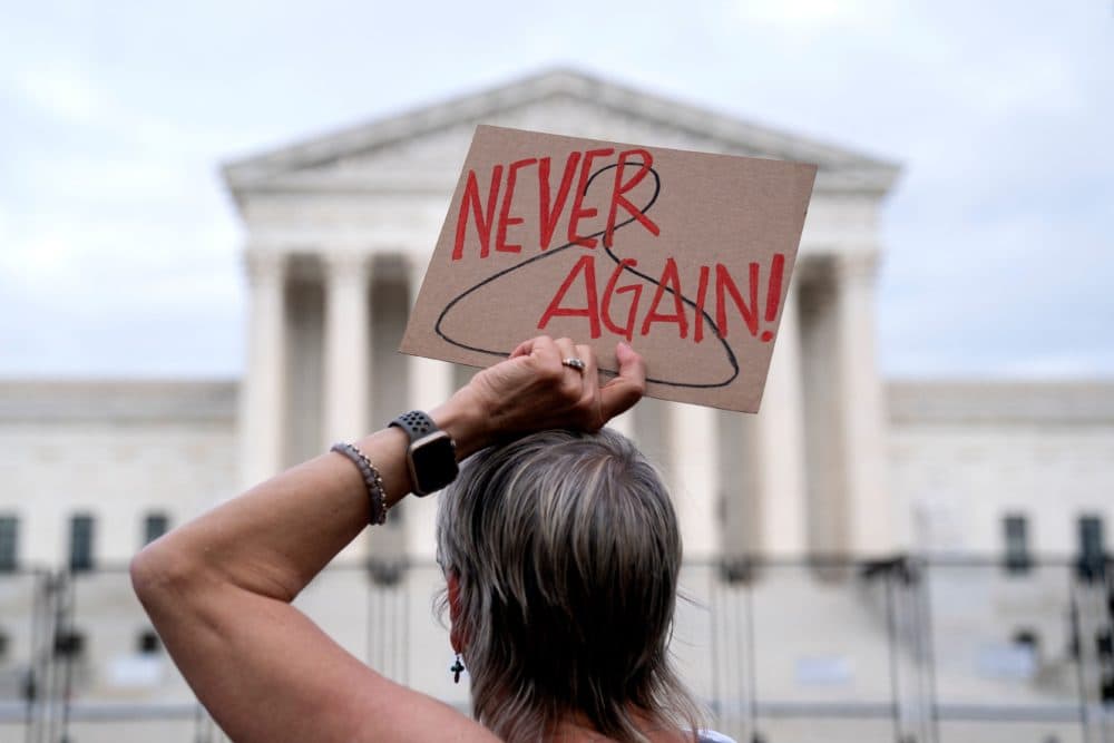 An abortion rights supporter holds a sign with a coat hanger, a symbol of the reproductive rights movement, with the words 'Never Again' in front of the US Supreme Court in Washington, DC, on May 11, 2022. (Stefani Reynolds/AFP via Getty Images)