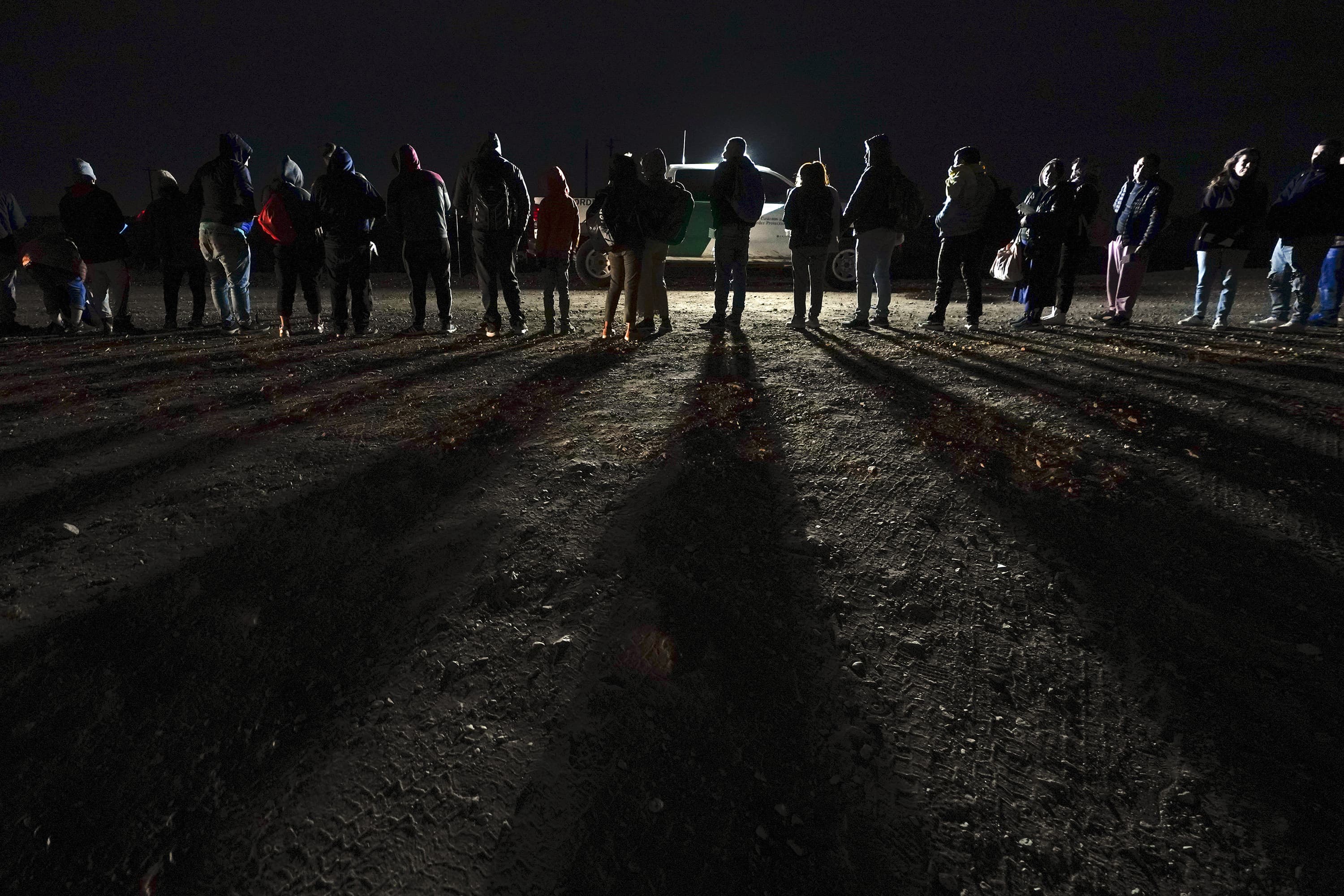 Migrants wait to be processed to seek asylum after crossing the border into the United States on Jan. 6 near Yuma, Ariz. (Gregory Bull/AP)
