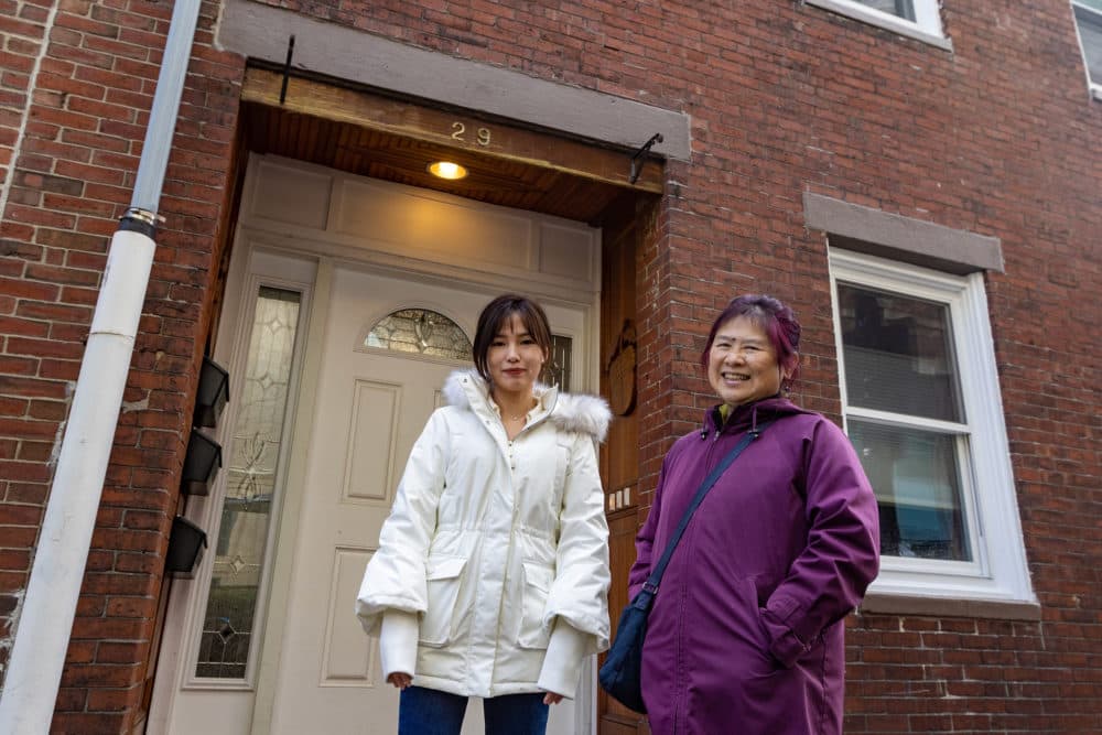 Executive Director Lydia Lowe, right, of the Chinatown Community Land Trust, stands with resident Meidan Lin outside of Lin's Oak Street home. (Jesse Costa/WBUR)