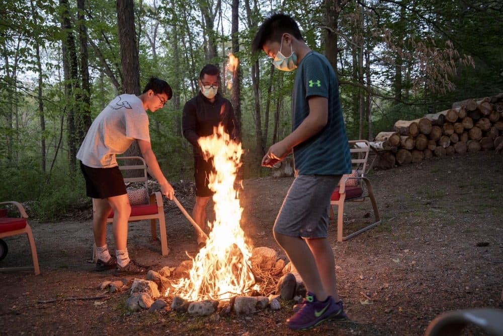 Frank Chein and his sons Alfie and Luca spend an evening by a campfire near their home in Hamilton Mass. (Robin Lubbock/WBUR)