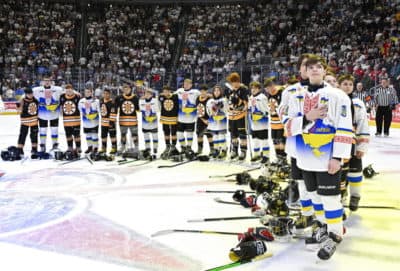Ukraine and Boston Junior Bruins peewee teams stand together during the national anthems before a hockey game, Saturday, Feb, 11, 2023, in Quebec City. (Jacques Boissinot/The Canadian Press via AP)