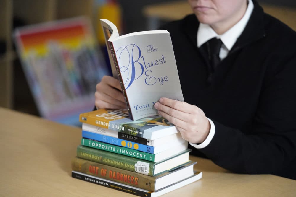 An educator poses with books, including &quot;The Bluest Eye,&quot; by Toni Morrison, that have been the subject of complaints from parents in Salt Lake City, Utah. The wave of book bannings around the country has reached a level not seen for decades. (Rick Bowmer/AP)