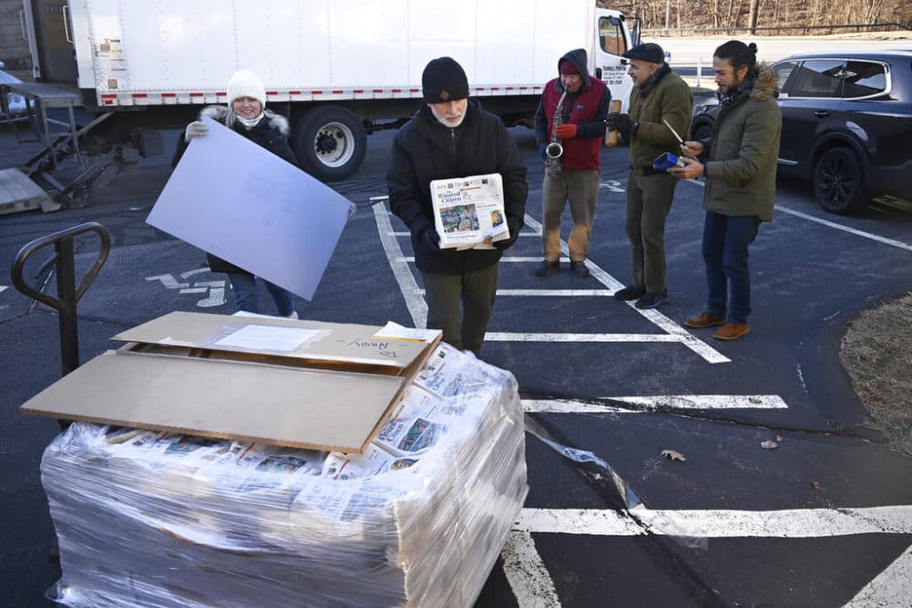 Andy Thibault, Editor and Publisher of The Winsted Citizen, carries the first bundle of papers off a pallet as Advertising and Circulation Director Rosemary Scanlon holds the first print press plate while a group of musicians play behind them after the arrival of the first delivery of the paper on Feb. 3. (Jessica Hill/AP)
