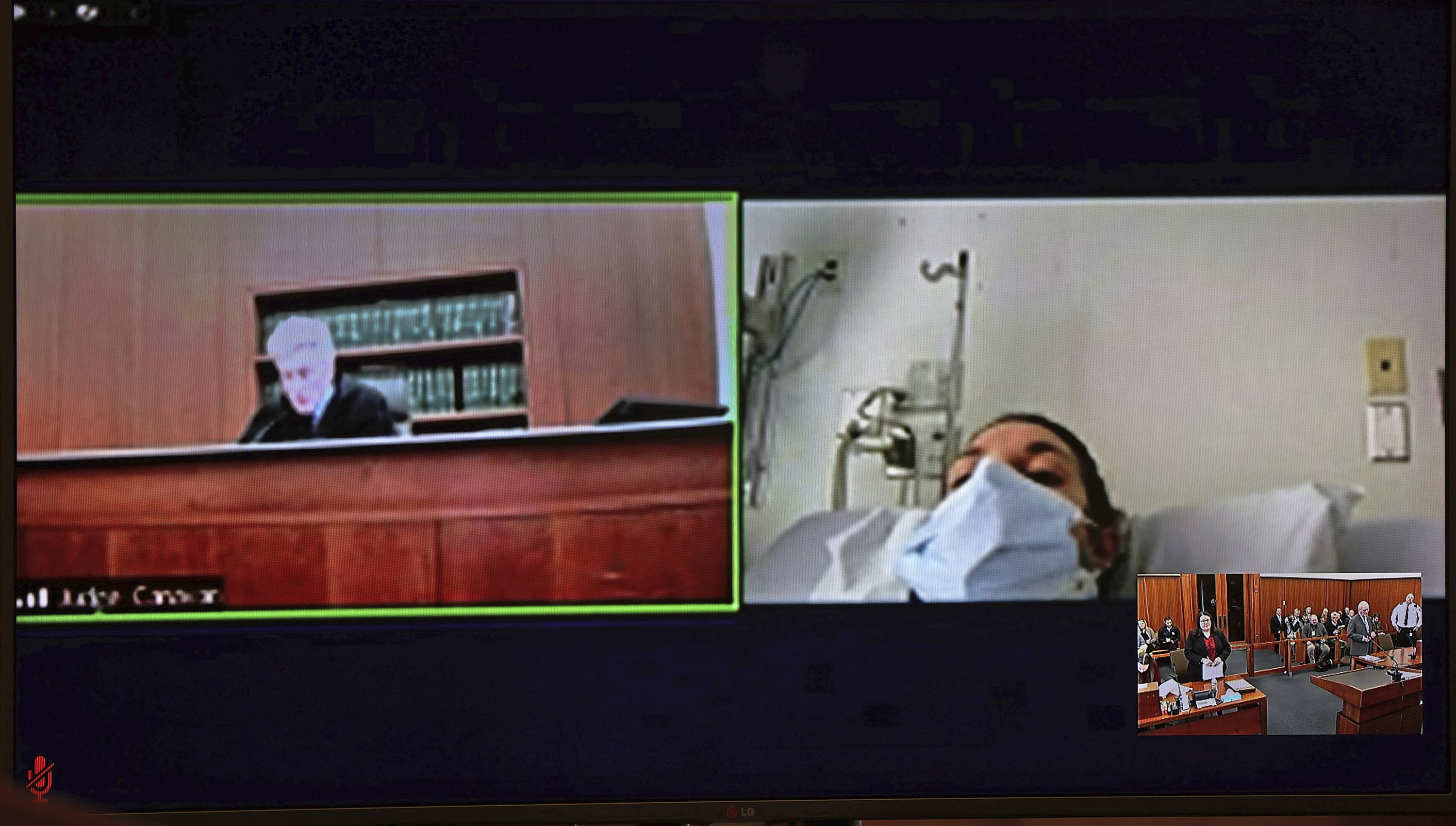 In this video screen image, Lindsay Clancy, with a surgical mask over her face in a hospital, appears during her arraignment on charges regarding her three children's deaths at Plymouth District Court. With District Court Judge John Canavan, top left, as the presiding judge the defendant participated remotely through videoconference. (David Ryan/The Boston Globe via AP, Pool)