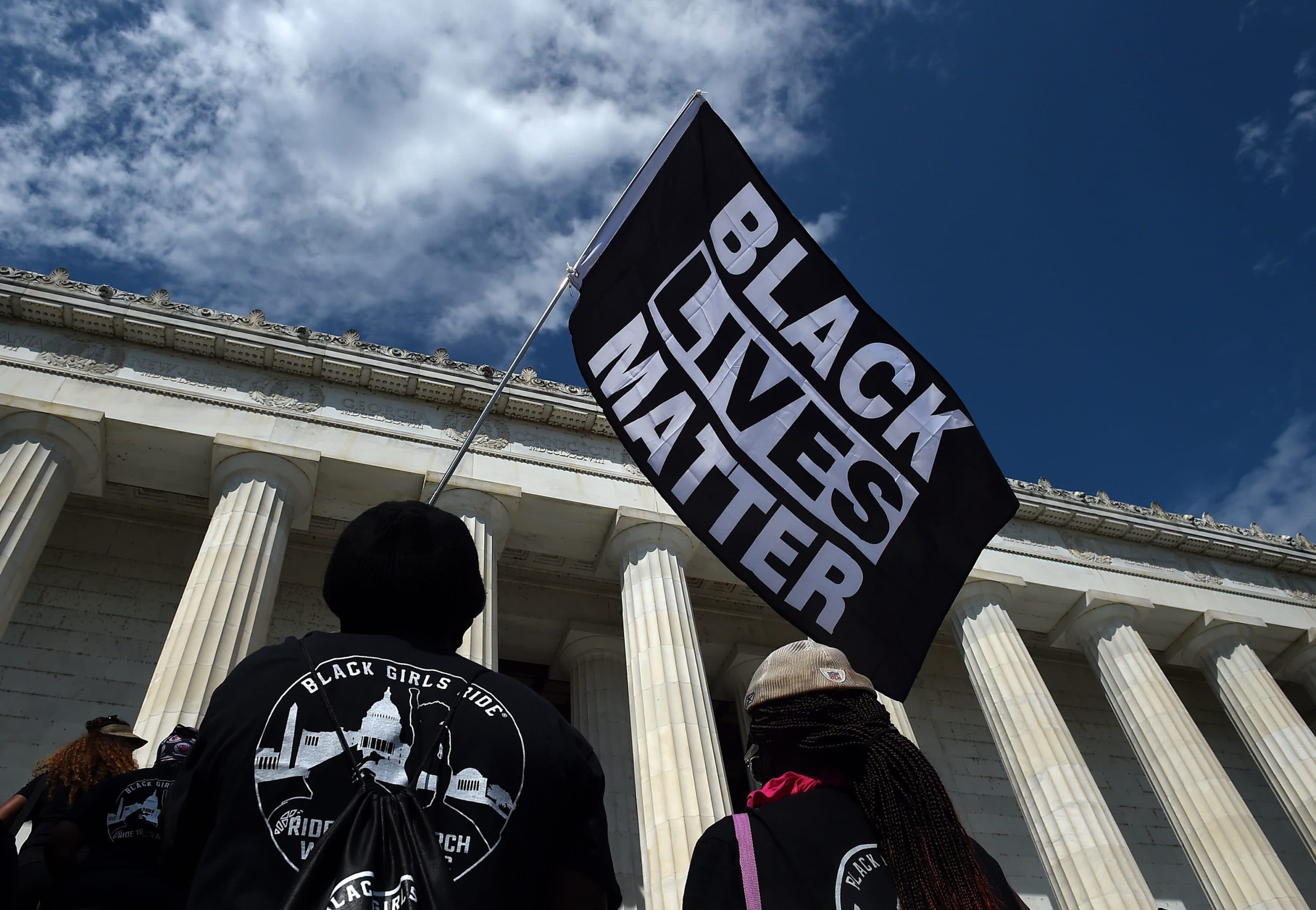 A person holds a Black Lives Matter flag during the &quot;Commitment March: Get Your Knee Off Our Necks&quot; protest against racism and police brutality, at the Lincoln Memorial on August 28, 2020, in Washington DC. (Olivier Douliery/POOL/AFP via Getty Images)