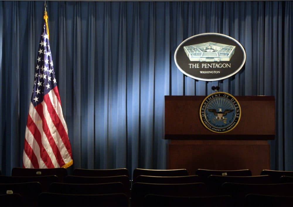 The Pentagon logo and an American flag are lit up January 3, 2002 in the briefing room of Pentagon in Arlington, VA. (Photo by Alex Wong/Getty Images)
