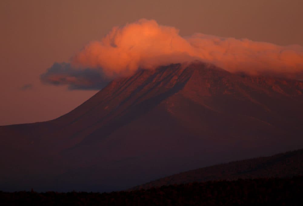 In this Aug. 7, 2017, file photo, the first rays of sunlight color the clouds over Mount Katahdin in this view from Patten, Maine. (Robert F. Bukaty/AP)