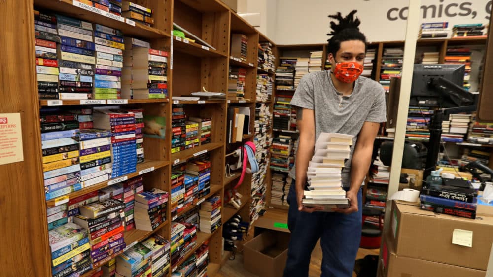 A man carries books in a bookstore. (Tony Dejak/AP)