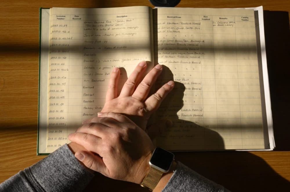 The hands of archivist Kathy Craughwell-Varda rest on a ledger she created of a small portion of the gifts sent to Sandy Hook in the wake of the 2012 massacre at Sandy Hook Elementary School. Thousands of teddy bears, toys, school supplies, cards and letters were sent to Newtown from all over the world. (Mark Mirko/Connecticut Public)
