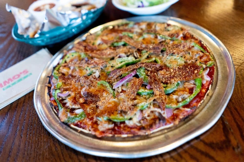 A “Deluxe” St. Louis-style pizza topped with sausage, mushrooms, onions, green pepper, bacon, and Provel cheese alongside toasted ravioli and a house salad on Thursday, Oct. 6, 2022, at Imo’s Pizza in St. Louis’ Downtown West neighborhood. (Brian Munoz/St. Louis Public Radio)