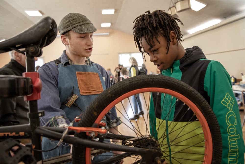 Bike repair volunteer Paul Rhodes shares tune up tips with bicycle owner Abdul Senusi at Framingham's Repair Cafe. (Robin Lubbock/WBUR)
