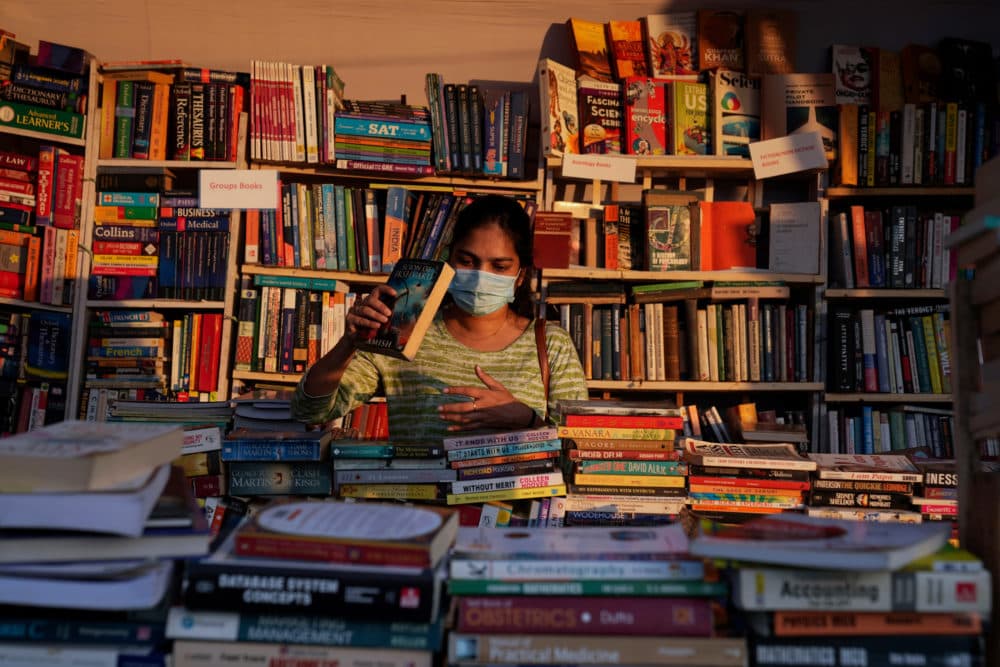 A visitor wearing face mask as a precaution against COVID-19 browse through books. (Mahesh Kumar A./AP)