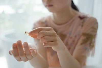 Girl taking a vitamin or omega-3 supplement capsule. (Getty Images)
