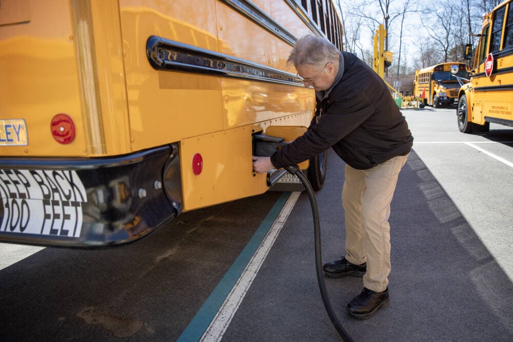 District transportation director Dana Cruickshank unplugs the charging cable from one of Beverly's electric school buses. (Robin Lubbock/WBUR)