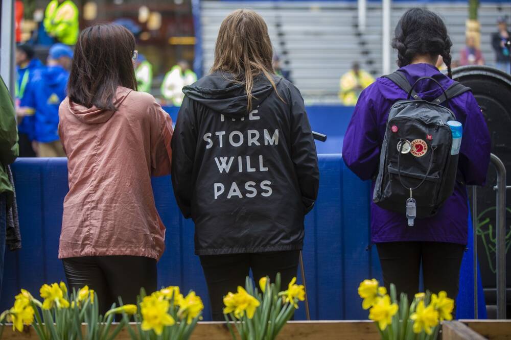 A woman with a jacket that read, “The Storm Will Pass,” watches things happening on the course. (Jesse Costa/WBUR)