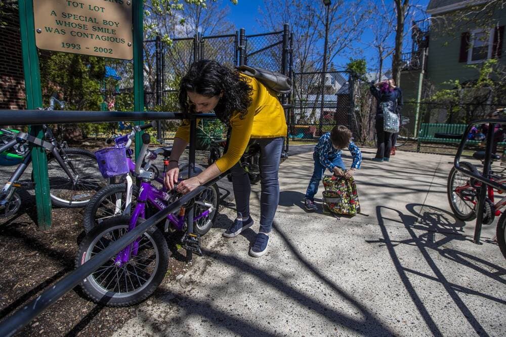 A mother unlocks her son's bicycle before heading home for the day. (Jesse Costa/WBUR)