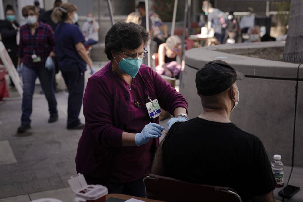 Registered nurse Julie Hurtado, left, administers the COVID-19 vaccine to a man in Los Angele. (Jae C. Hong/AP)