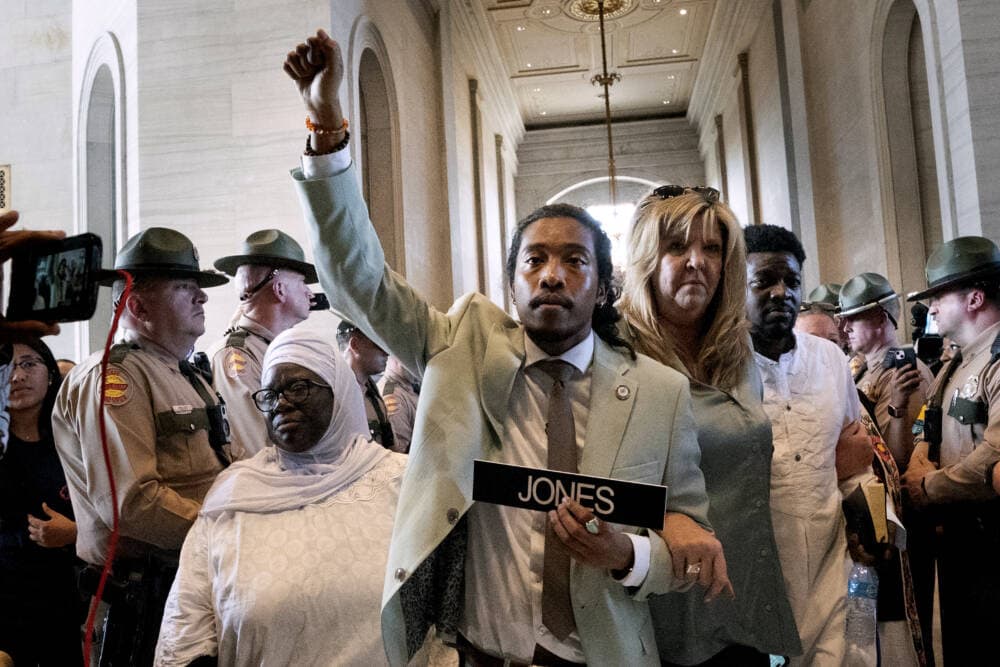 Metro Nashville Council member Zulfat Suara, left, and State Rep. Gloria Johnson, D-Knoxville, right, escort State Rep. Justin Jones, D-Nashville, center, back to the House chamber. (George Walker IV/AP)