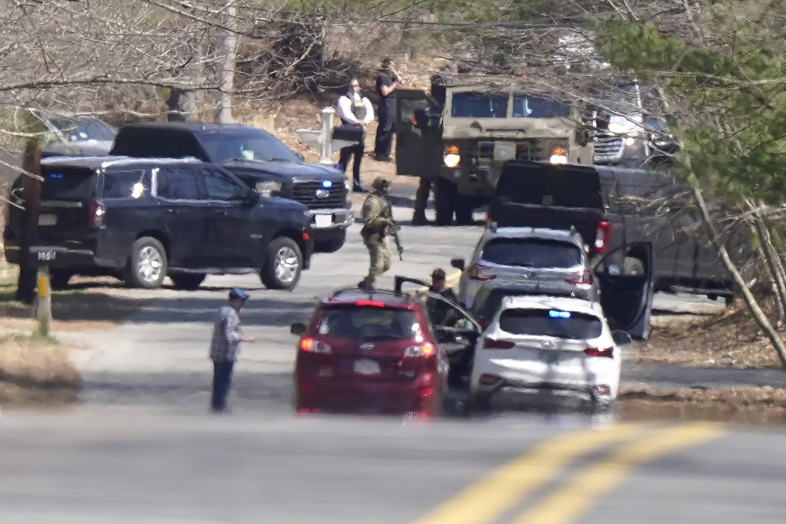Members of law enforcement assemble on a road, Thursday, April 13, 2023, in Dighton, where FBI agents converged on the home of a Massachusetts Air National Guard member who has emerged as a main person of interest in the disclosure of highly classified military documents. (Steven Senne/AP)