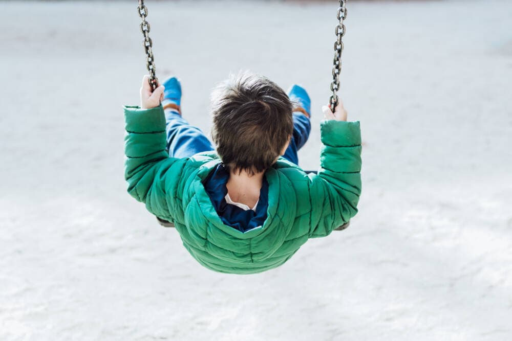 A four-year old boy on a playground swing. (Getty Images)