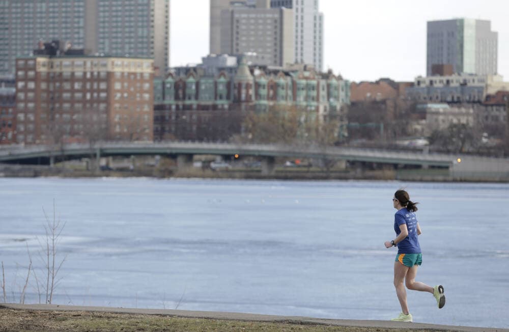 A runner makes her way along a path next to the Charles River Monday, Feb. 1, 2016, in Cambridge, Mass. Temperatures were above 60 degrees in many places in Massachusetts Monday. The Boston skyline is visible behind. (AP Photo/Steven Senne)