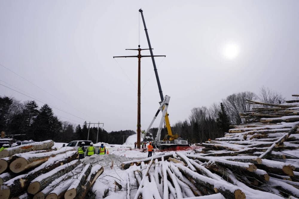 Workers connect a section of the first pole of Central Maine Power's controversial hydropower transmission corridor, Feb. 9, 2021, near The Forks, Maine
