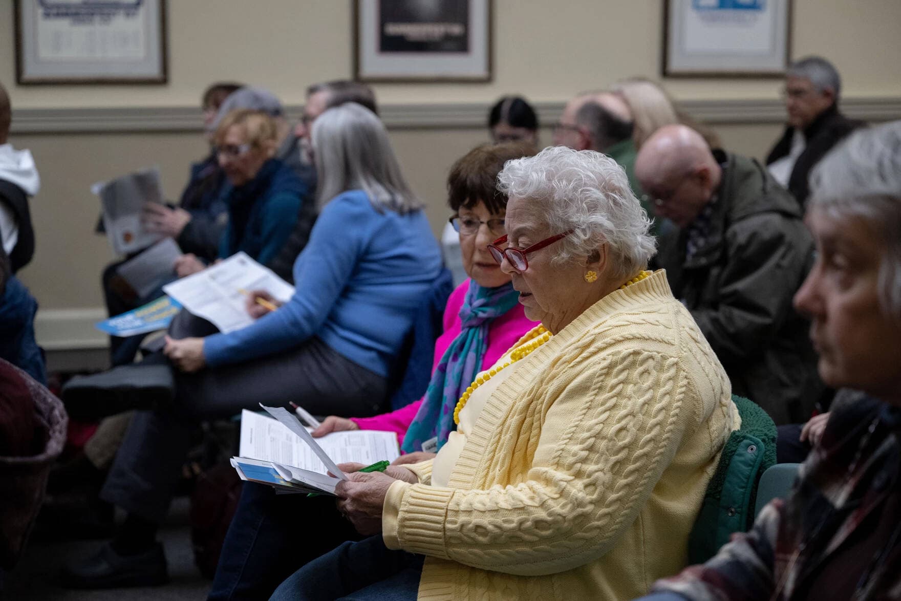 Nashua residents Pat Lyons, center right, and Irene Oliveira look at informational sheets on April 5, during a meeting about community power at City Hall in Nashua, N.H. (Raquel C. Zaldívar/New England News Collaborative)
