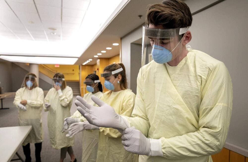 A clinical care technician pulls on gloves during a protective equipment training session at Tufts Medical Center in early 2020. (Robin Lubbock/WBUR)