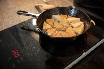 Tofu sizzles on an induction portable cooktop. (Robin Lubbock/WBUR)