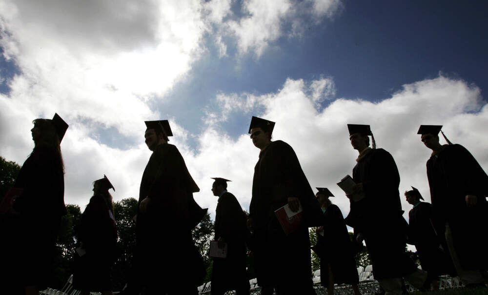 Students walk wearing their caps and gowns. (Mel Evans/AP)