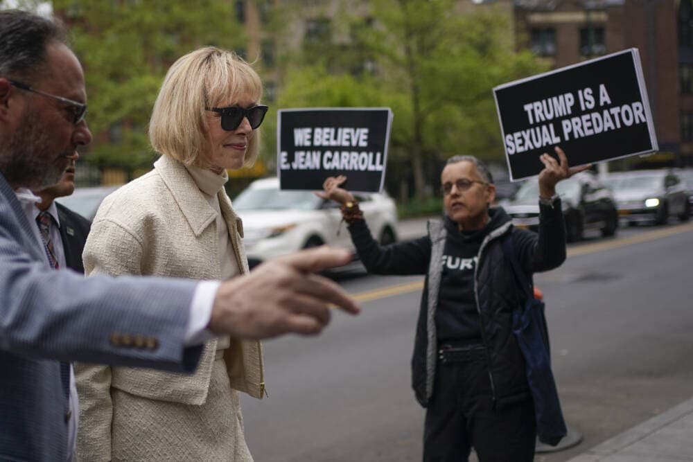 While a protester holds up signs, E. Jean Carroll arrives to federal court in New York on April 27, 2023. (Seth Wenig/AP)