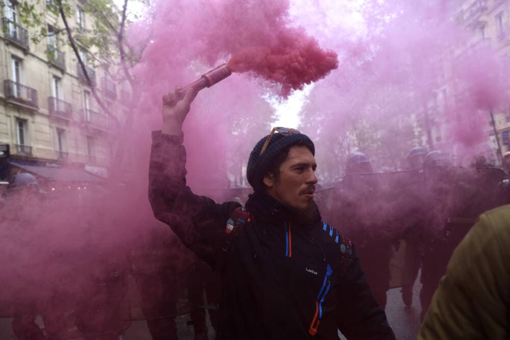 A protester holds a pink flare during a demonstration in Paris. (Aurelien Morissard/AP)