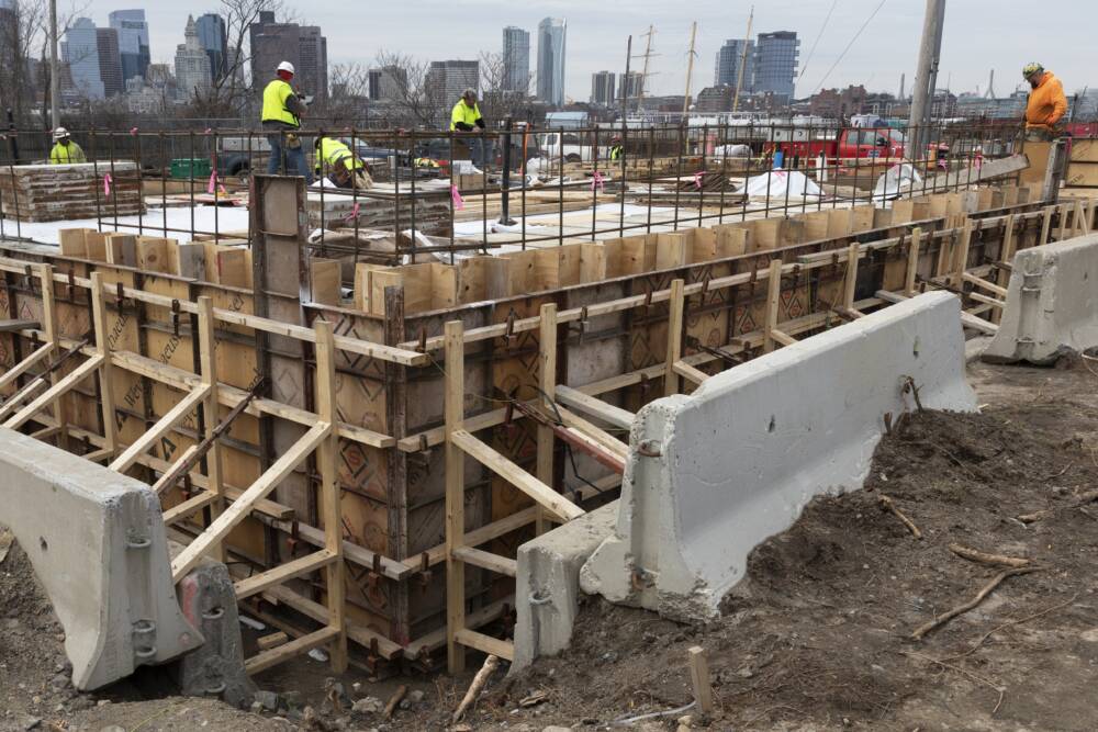 Construction workers prepare a recently poured concrete foundation, Friday, March 17, 2023, in Boston. (AP Photo/Michael Dwyer)