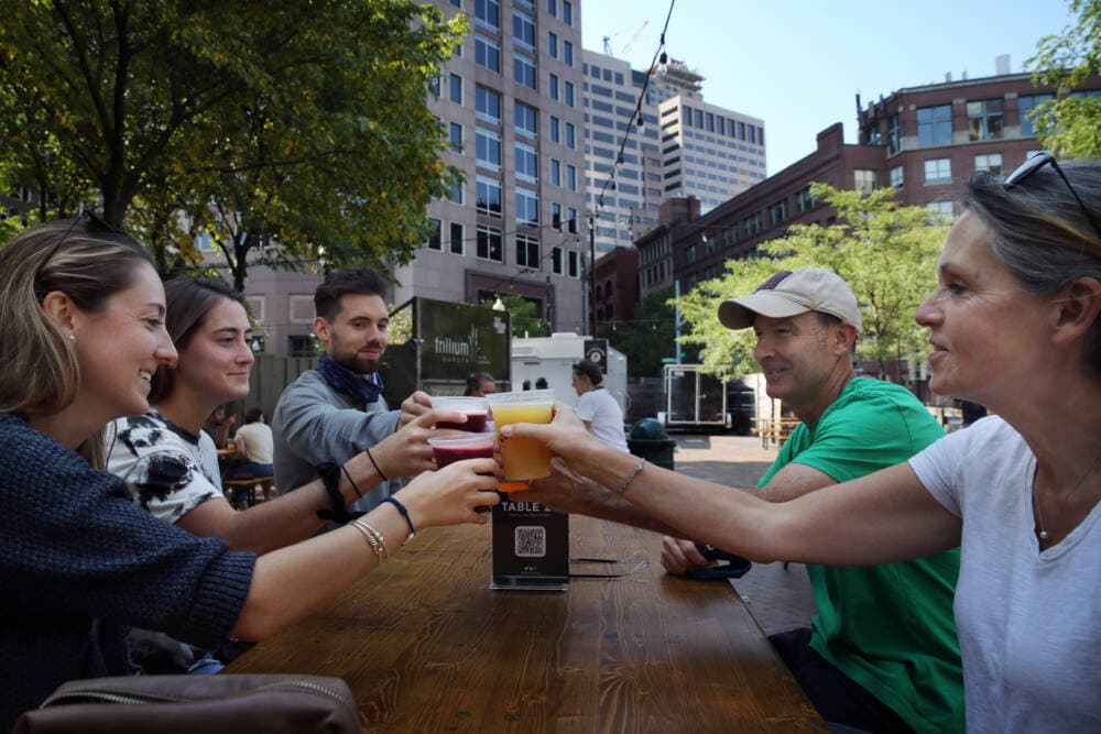 A group of people cheers at Trillium's beer garden on the Rose Kennedy Greenway in Boston. (Craig F. Walker/The Boston Globe via Getty Images)