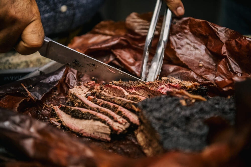 A chef cuts slices of brisket during. (Brandon Bell/Getty Images)