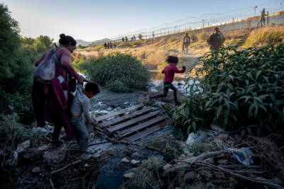 Immigrants step over a trickle of the Rio Grande while crossing the border from Mexico hoping to be processed for asylum on May 08, 2023 in El Paso, Texas. (John Moore/Getty Images)