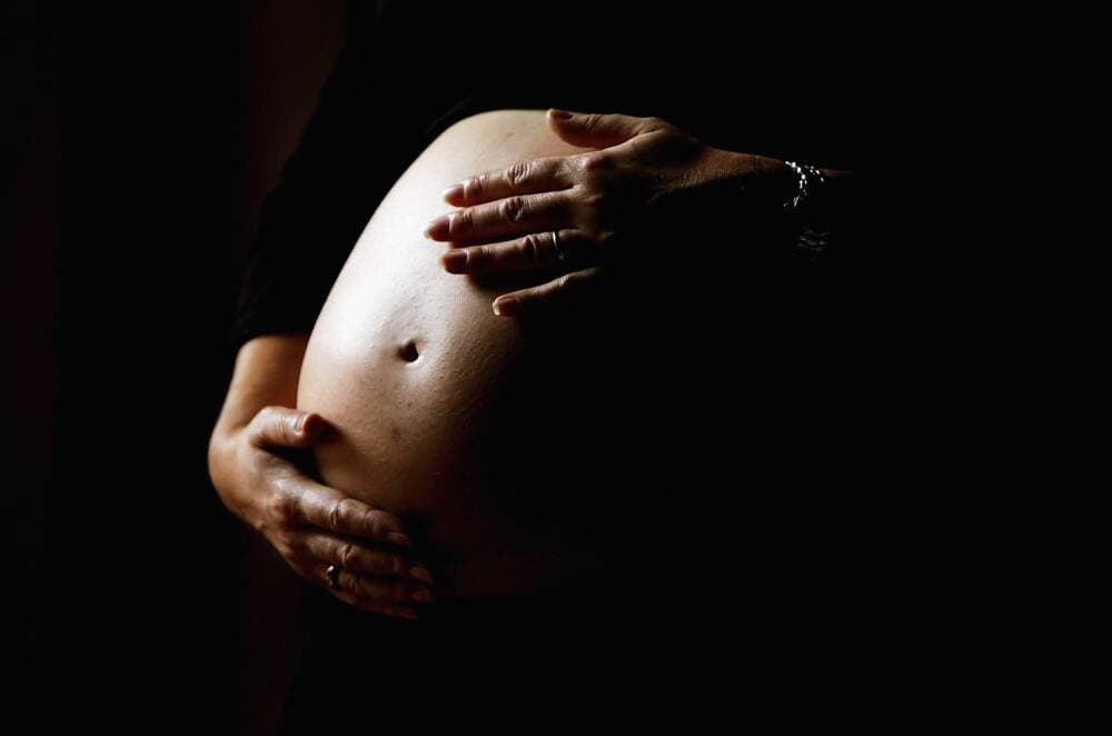 A pregnant woman holds her stomach. (Ian Waldie/Getty Images)