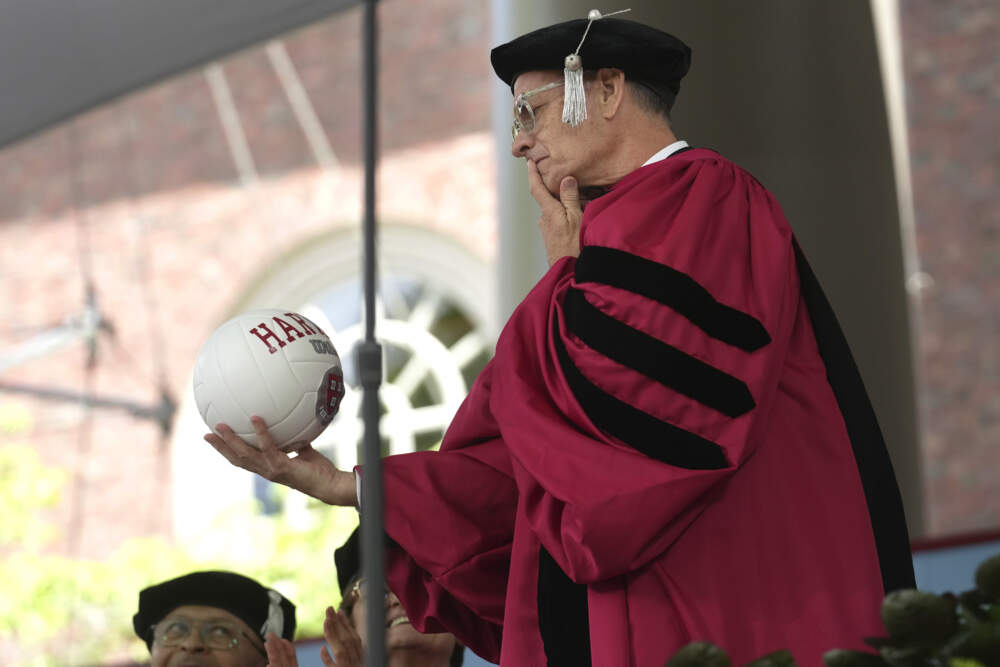 Actor Tom Hanks examines a ball as part of a spoof during Harvard University commencement exercises on the school's campus, Thursday, May 25, 2023, in Cambridge, Mass. (Steven Senne/AP)