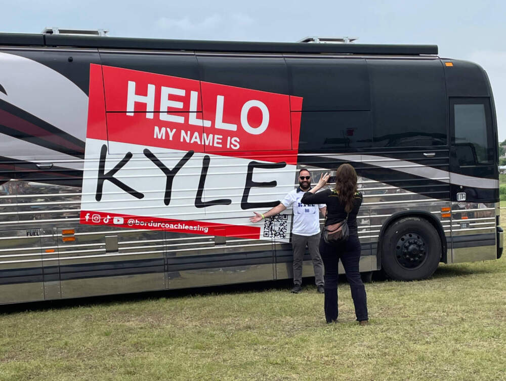 One of the many people named Kyle at the recent Kyle Fair in Kyle, Texas, stands in front of a Kyle bus. (Kyle Gassiott/Troy Public Radio)