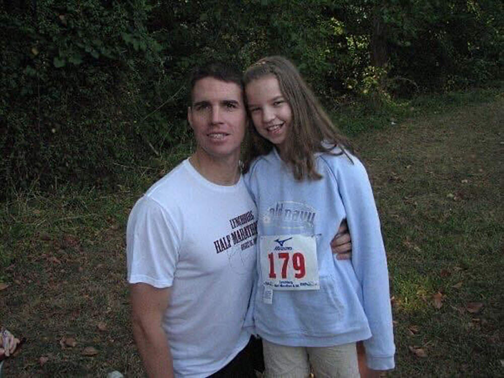 Bailey Donahue, then 11 years old, poses with her dad, Army Major Mike Donahue, while wearing his race bib. (Courtesy Bailey Donahue)