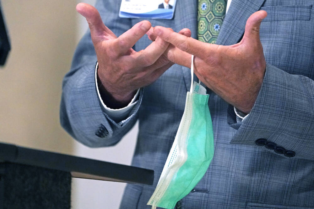 A mask hangs from a doctor's hand during a press conference. The relaxation of Massachusetts' face covering requirement for health care facilities is one of many COVID policy changes happening Thursday as the state's public health emergency declaration expires. (Rogelio V. Solis/AP Photo)